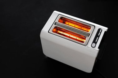 Yukarıdan, ekmek olmadan siyah zemin üzerinde çalışan modern beyaz ekmek kızartma makinesine bakın, yemek pişirmek için elektrikli aletler. Mutfak aletleri konsepti