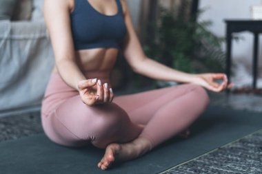 Refah ve refah kavramı. Sportif ve sağlıklı bir kadının yoga yapması, yarım lotus meditasyon pozu vermesi, ardha padmasana egzersizi yapması, Mudra jesti ile ellerini kapaması.