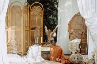 Ahşap dizaynlı fotoğraf bölgesi, kırsal alan arka planı. Boho terasında beyaz perdeli kimse yok. Hasır mobilyaların yanındaki kuru saman fabrikası, kırsal dekorasyon konsepti..
