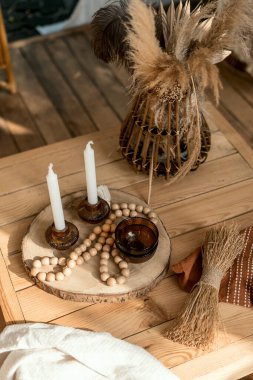 Masada ahşap dekor, rahat ev dekorasyonu. Doğal detaylara dikey yakın çekim, basit bir köy tarzı. Mumlarla klasik dekorasyon, vazoda kuru bitki..