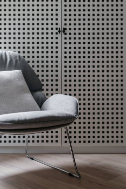 Ev tasarımı, modern sandalyeye yakın çekim. Rahat mobilyaları ve yastık dekoru olan gri oturma odası. Koltuğun arkasındaki ev deposu, İskandinav tarzı zarif bir daire..