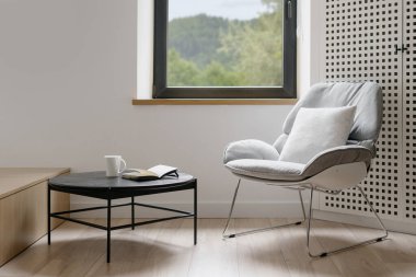 Modern oturma odası tarzı, iç mekan. Mobilyalı ev tasarımı, minimalist bir daire. Pencerenin yanındaki rahat sandalye, koltuk dekorasyonu. Masalı çağdaş iç mekan.