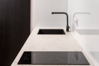 Evdeki beyaz mutfak, modern iç mekan. Ev yapımı siyah sobası, lavabosu ve musluğu olan lüks minimalist bir tezgah. Çelik mobilyaların modern tasarımı, odada kimse yok..