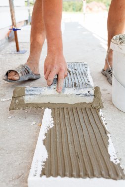 İnşaat işçisi bir alçı strafor spatula ile koyar