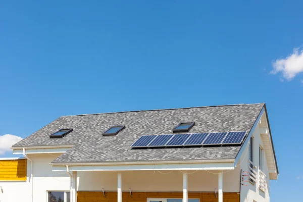 Солнечная водяная панель отопления на крыше нового дома с люками против голубого неба — стоковое фото