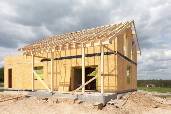 New residential frame house under construction against a blue sky — Stock Photo, Image