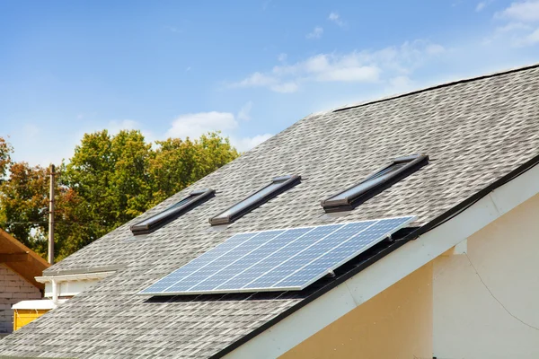 Calentamiento solar del panel de agua en el techo de la casa nueva con tragaluces contra el cielo azul —  Fotos de Stock