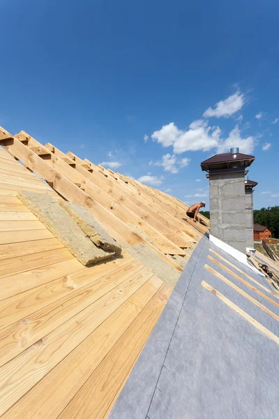 Dachisolierung. Neues Holzhaus im Bau mit Schornsteinen vor blauem Himmel — Stockfoto