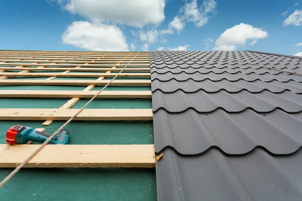 House under construction.Roof with metal tile,screwdriver and roofing iron — Stock Photo, Image