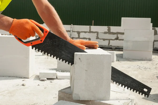 Worker cutting aerated block with a hand saw outdoor — Stock Photo, Image