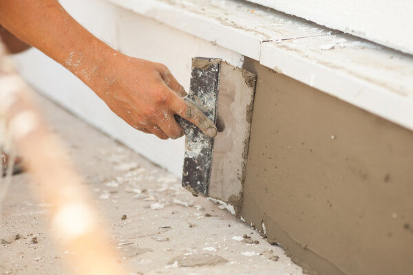 Man hand with trowel plastering a foundation of house