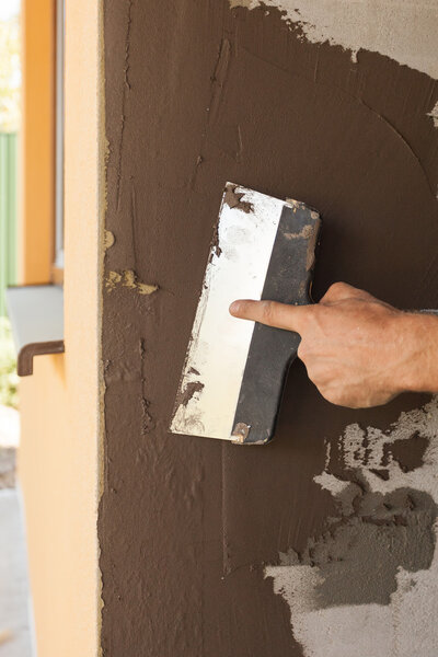 Man hand with trowel plastering a house wall