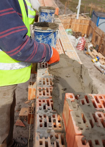 Работник строительства кирпичных стен на стройплощадке дома, кирпич и цемент — стоковое фото