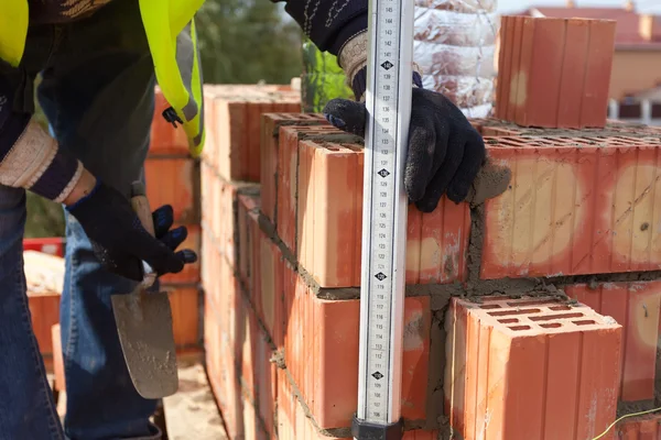 Albañil de construcción mide el espesor de las costuras en el ladrillo — Foto de Stock