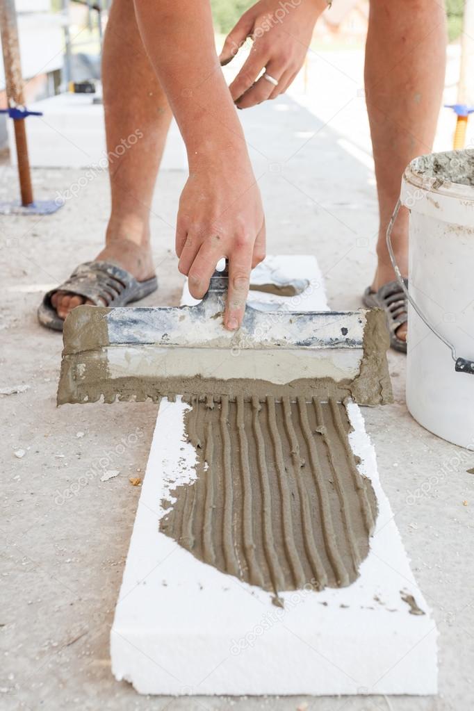 Construction worker puts a gypsum on styrofoam with spatula