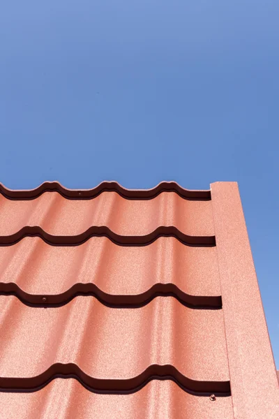 Telha de metal vermelho contra o céu azul — Fotografia de Stock