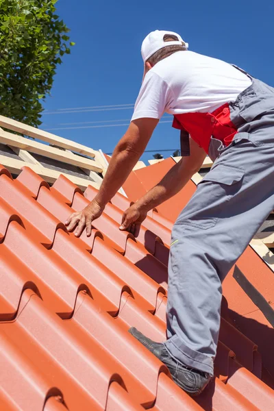 Travailleur sur un toit avec perceuse électrique installant des tuiles métalliques rouges sur une maison en bois — Photo