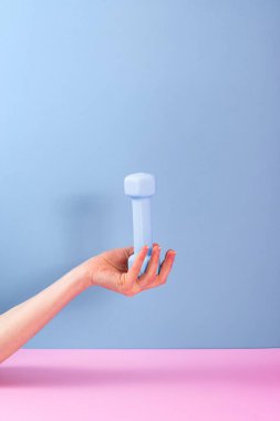 Açık mavi bir dambılı destekleyen bir el ev egzersizlerinin önemini gösterir. Canlı pembe ve mavi arkaplan fitness meraklıları için görsel cazibeyi artırıyor.