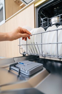 Modern bir bulaşık makinesinden, şık bir mutfakta bulunan temiz bulaşık sepetinin olduğu el çekme sepeti. Çağdaş bir ev ortamında ev aletleri kavramları.