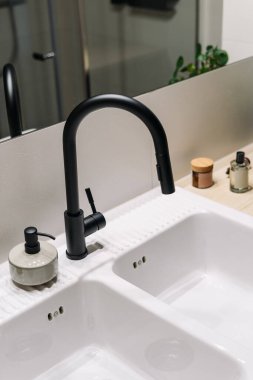 Modern bir banyo lavabosu, parlak bir musluk ve çeşitli bakım malzemeleriyle süslenmiş. Sıcak ortam, güne başlamak için mükemmel, ferahlatıcı bir kişisel bakım rutinini davet ediyor..