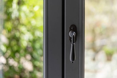 Konforlu bir oturma odasındaki ayarlama kulplu modern pencere çerçevesi, yerleşim alanına doğal ışık ve konfor sağlayan yemyeşil bir bahçe manzarasına açılır. Açık havada eğlenmek için mükemmel.