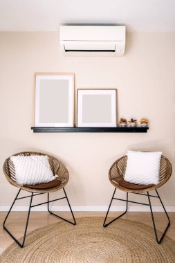 Konforlu yaşam alanı, iki zarif sandalye dekoratif eşyalarla süslü şık bir raf ve nötr bir zemin içeriyor. Rahatlamak için mükemmel bir sakinlik yaratıyor. Klimalı bir oda.