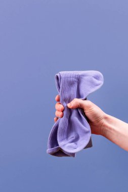 Bir el renkli bir çift pamuk çorabı kavrayıp dokularını ve tasarımlarını sergiliyor. Parlak arka plan, günlük giysiler için mükemmel olan bu aksesuarın neşeli ve gündelik doğasını geliştirir..