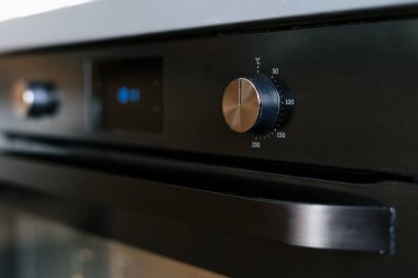 Modern elektrikli fırının seçici odak noktası şık düğmeler ve dijital ekran, gelişmiş teknolojisini şık bir mutfak ortamında pişirmek ve pişirmek için mükemmel gösteriyor..