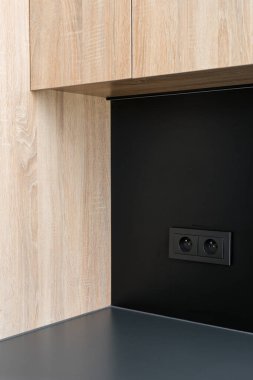 Siyah soket, oturma odasında ya da mutfakta elektrik prizi. Modern iç mekan vitrinleri ahşap dolaplar granit bir tezgahla eşleştirilmiş. Depolama çözümleri ve minimalist tasarım, dikey çekim