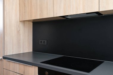 Ev aletleri, mutfak sobası, sökücü başlığı. İç mekanlarda zarif ahşap dolapları ve siyah tezgahları olan çağdaş bir tasarım sergileniyor..