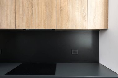 Bu modern mutfak pürüzsüz siyah bir tezgahın üzerinde cam seramik soba ile zarif ahşap dolaplar içerir. Çağdaş bir ev ortamında kusursuz bir harmanlama stili ve işlevselliği vardır..