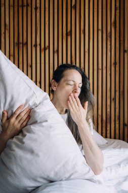 Alarmlı saat sabahın erken saatlerinde kadını uyandırır. Dişi esniyor, ağzı kapalı yatakta oturuyor, kendini yorgun hissediyor, yastığa sarılıyor, daha fazla dinlenmeye ya da uyku hapına ihtiyacı var. Uykusuzluk kavramları