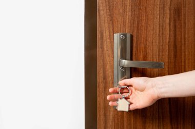 Yakın çekimde, evin anahtarını ahşap bir ön kapının anahtar deliğinde tutuyor. Güvenlik, ev sahipliği, satın alma ya da kiralık ev kavramları. Otel odasını açan kadın, kendini kontrol et..