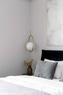 Bu otel odasında, düzenli yapılmış bir yatak, dekoratif yastıklar ve zarif başucu dekorlarıyla minimalist bir iç mekan sergilenerek misafirler için rahat bir atmosfer yaratılıyor..