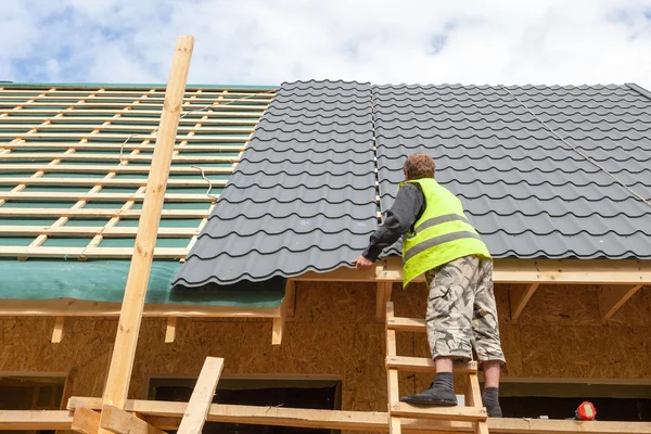 Dachdecker verlegt einen Metallziegel auf ein neues Holzhaus — Stockfoto