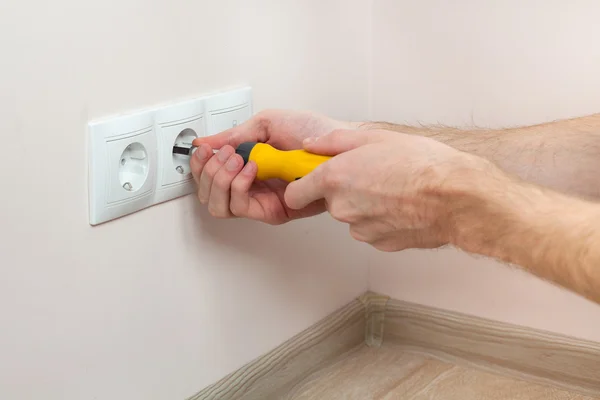 As mãos de um eletricista instalar uma tomada de energia de parede — Fotografia de Stock