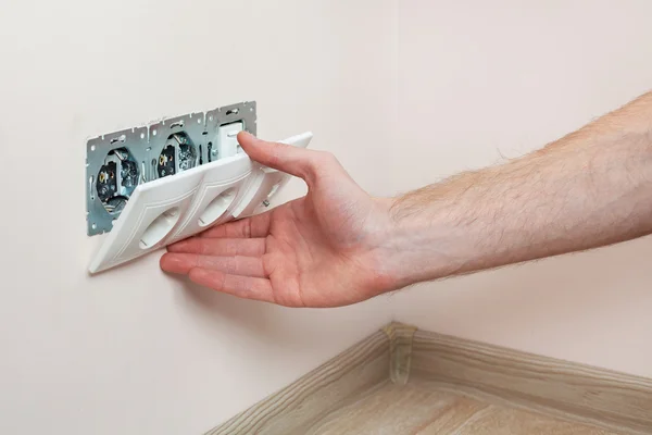 As mãos de um eletricista instalar uma tomada de energia de parede — Fotografia de Stock