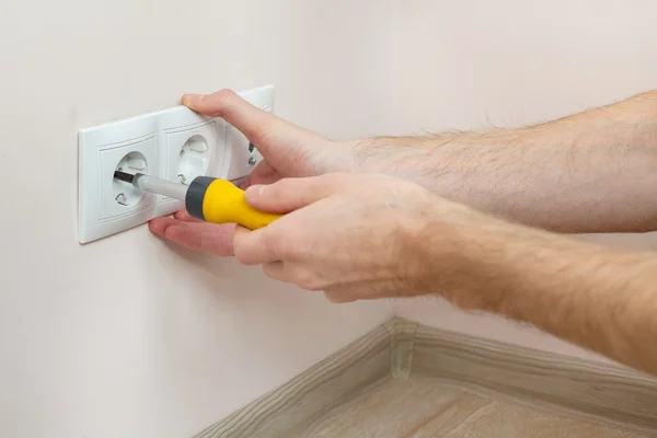 De handen van een elektricien voor het installeren van een muur stopcontact met schroevendraaier — Stockfoto