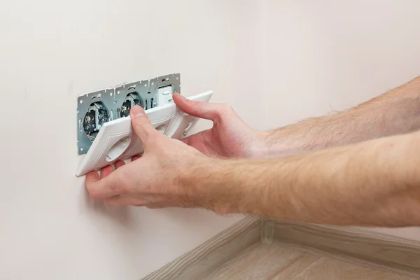 As mãos de um eletricista instalar uma tomada de energia de parede — Fotografia de Stock