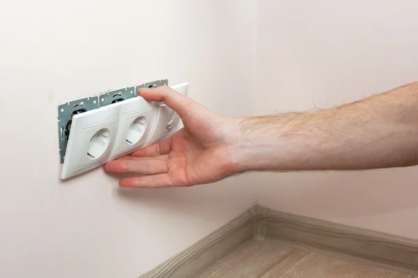 As mãos de um eletricista instalar uma tomada de energia de parede — Fotografia de Stock