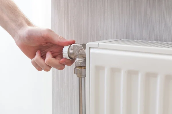 Radiator adjustment closeup. Man's hand adjusting radiator temperature.