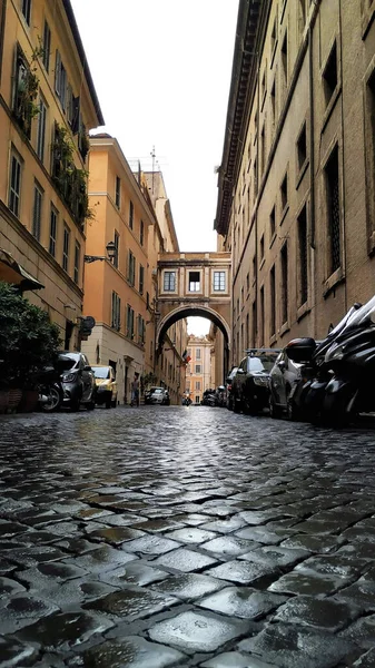 all roads lead to rome. wet street of rome with several cars parked. rainyt day in rome, italy