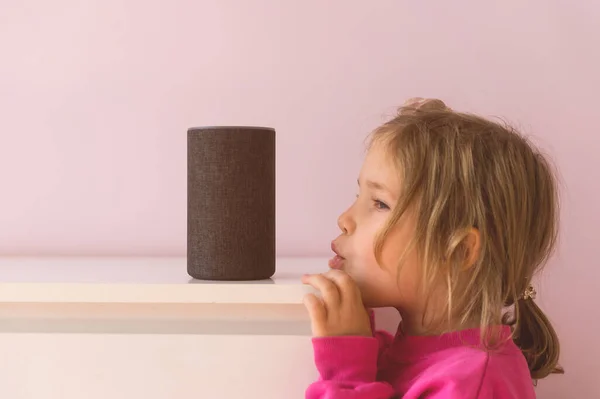 Ses kontrollü akıllı konuşmacı. Küçük kız Amazon Alexa Echo Dot ile konuşuyor. Çocuklar için eğitim programı. Küçük kız Alexa 'yla konuşuyor ve ona emirler verip neyi açacağını söylüyor.