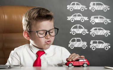 Okul çocuğu iş adamı. Çocuk uzmanı kırmızı oyuncak arabayı test ediyor. Hangi arabayı alacağına karar vermek. Çocuk ofiste oturuyor ve arabasını hayal ediyor. Gelecek ve para eğitimi.