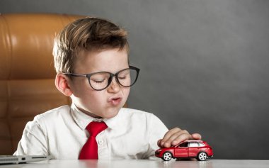 Kırmızı oyuncak arabayla oynayan küçük bir iş adamı. Çocuk çocuk araba hakkında rüya görüyor. Çocuklar için işletme okulu.