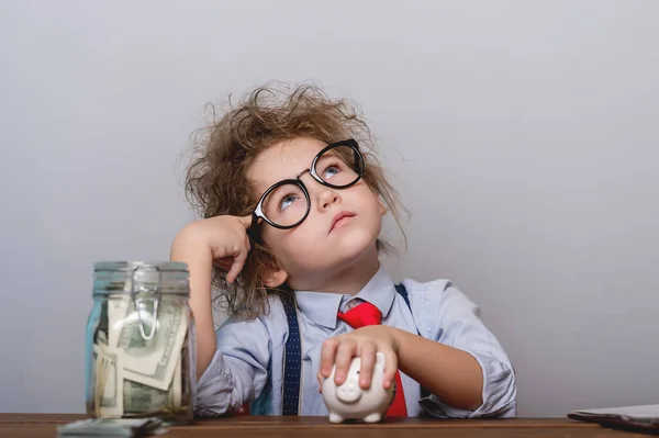 Kid and money. Funny child plays with money and bills. Education for little businessman how to be rich when grow up. Piggy bank and jar full of money. Idea dream investment concept