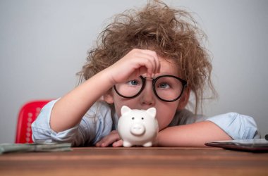 Çocuk para biriktiriyor. Küçük çocuk gelecek eğitim için para biriktiriyor. Masadaki çocuk para sayıyor. Okula dönelim. Finansal sorumluluk öğrenme ve tasarruf hedefleme