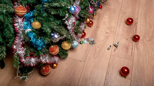 Fallen Christmas tree and shattered christmas ball on the floor. Happy holiday and the end of Christmas. Fault of the kid — Stock Photo, Image