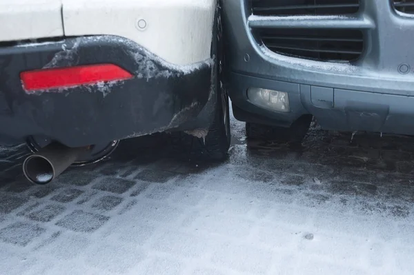 Buzlu kar yolunda iki otomobilin çarpışmasını içeren bir araba kazası. Kışın bir şehir caddesinde kaza yapan iki araba birbirine yaklaşıyor. Kırık tampon.