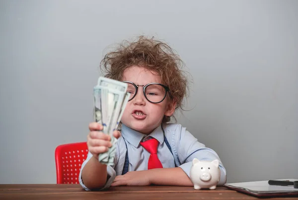 Funny angry kid boss with money. Portrait of angry displeased little child with freckles isolated over white background wearing glasses and suit. Child clenches money in a fist — Stock Photo, Image